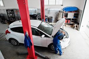 tema riparazione e manutenzione auto. meccanico in uniforme che lavora in servizio auto. foto