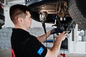 tema riparazione e manutenzione auto. meccanico in uniforme che lavora in servizio auto. foto