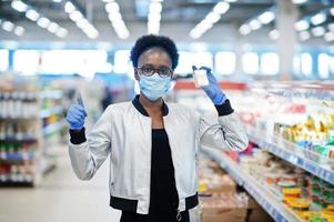 donna africana che indossa maschera medica monouso e guanti che acquistano al supermercato durante l'epidemia di pandemia di coronavirus. tempo epidemico. foto