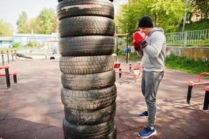 uomo pugile arabo in cappello che si allena per una dura lotta in palestra all'aperto. foto