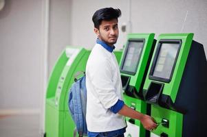 il giovane uomo asiatico ha messo la sua carta di credito per rimuovere i contanti da un bancomat verde. foto
