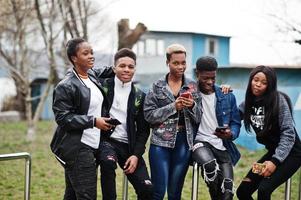 giovani amici africani millennial con i telefoni cellulari. felici neri che si divertono insieme. concetto di amicizia di generazione z. foto