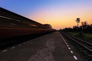 treno in movimento attraverso la stazione al tramonto foto