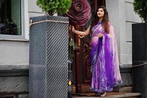 ragazza indù indiana al tradizionale saree viola poste in strada vicino a una grande rosa decorata. foto