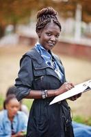 gruppo di cinque studenti universitari africani che trascorrono del tempo insieme nel campus nel cortile dell'università. amici afro neri che studiano. tema dell'educazione. foto