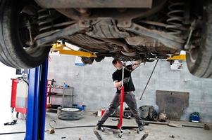 tema riparazione e manutenzione auto. meccanico in uniforme che lavora in servizio auto. foto