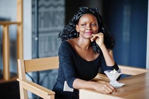 ragazza afroamericana seduta al bar e mangiare il gelato. foto