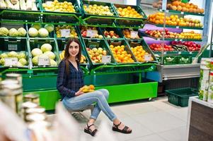 donna dello shopping guardando gli scaffali del supermercato. ritratto di una giovane ragazza in un negozio di mercato nella sezione di frutta e verdura. foto