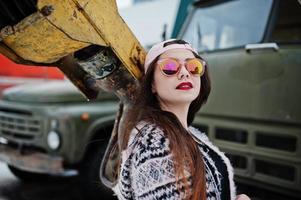 ragazza casuale alla moda castana nel cappuccio contro la vecchia gru del camion. foto