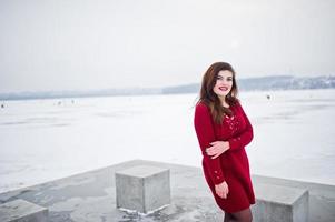 bruna modello taglie forti in rosso contro il lago ghiacciato in una giornata invernale. foto