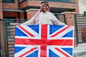 uomo arabo mediorientale posato su strada con bandiera della Gran Bretagna. concetto di inghilterra e paesi arabi. foto