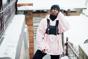 elegante uomo afroamericano in stile urbano in felpa con cappuccio rosa posato al giorno d'inverno. foto