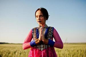 tenera ragazza indiana in saree, con labbra viola compongono poste in campo al tramonto. modello indiano alla moda. foto