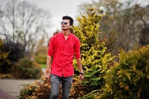 uomo indiano in camicia rossa e occhiali da sole poste all'aperto. foto