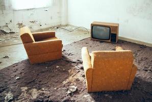 vecchio televisore sul pavimento e due sedie vintage foto