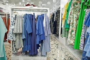 set di abbigliamento femminile colorato sugli scaffali nella nuovissima boutique moderna del negozio di abbigliamento. collezioni di abiti primavera estate. foto