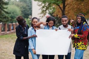 un gruppo di cinque studenti universitari africani nel campus del cortile dell'università tiene uno spazio vuoto bianco. spazio libero per il tuo testo. amici afro neri che studiano. foto