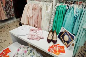 set di abbigliamento femminile colorato sugli scaffali con scarpe nel negozio di abbigliamento nuovissimo boutique moderno. collezioni di abiti primavera estate. foto