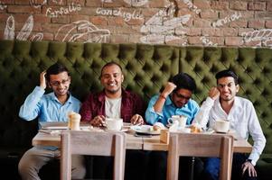 un gruppo di quattro uomini del sud asiatico poste alla riunione di lavoro nella caffetteria. indiani che guardano la tv e fanno il tifo per la loro squadra del cuore. foto