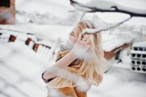 ritratto di ragazza bionda con gli occhiali, pelliccia rossa e sciarpa al giorno d'inverno. foto