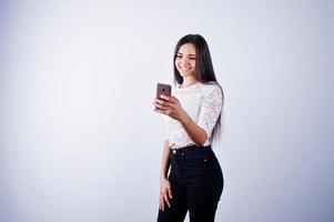 ritratto di una giovane bella donna in top bianco e pantaloni neri usando il suo telefono. foto