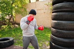 uomo pugile arabo in cappello che si allena per una dura lotta in palestra all'aperto. foto