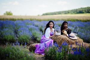 due belle ragazze indiane indossano abiti tradizionali indiani saree in un campo di lavanda viola. foto
