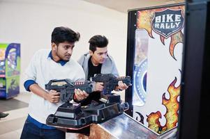 due ragazzi asiatici competono su una macchina arcade per giochi di simulazione sparatutto. foto