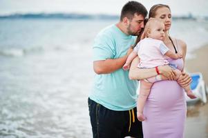 vacanze estive. genitori e persone attività all'aperto con i bambini. buone vacanze in famiglia. padre, madre incinta, figlia sulla spiaggia di sabbia del mare. foto