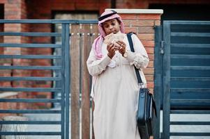 uomo d'affari arabo mediorientale posato su strada contro un edificio moderno con borsetta nera e denaro in euro. foto