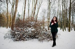 ragazza bruna in maglione verde e sciarpa rossa all'aperto il giorno d'inverno serale. foto