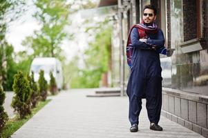 elegante uomo arabo musulmano indiano pakistano in abito kurta dhoti e occhiali da sole. foto