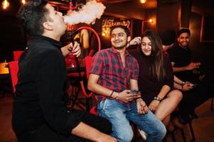 gruppo di amici indiani seduti al lounge bar, fumare narghilè e riposarsi. foto