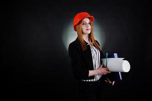 ingegnere donna in arancione protegge il casco con progetto di carta da costruzione. foto