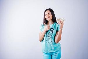 ritratto di una ragazza attraente in maglietta e pantaloni blu o turchese in posa con molti soldi in mano. foto