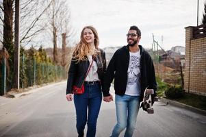 bella coppia multirazziale che cammina insieme al longboard. foto