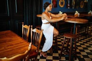 donna afroamericana, acconciatura retrò in abito bianco al ristorante. foto