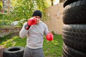 uomo pugile arabo in cappello che si allena per una dura lotta in palestra all'aperto. foto