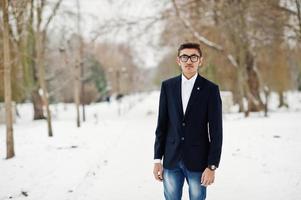 elegante studente indiano uomo in tuta e occhiali poste al giorno d'inverno all'aperto. foto