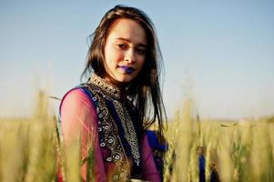 tenera ragazza indiana in saree, con labbra viola compongono poste in campo al tramonto. modello indiano alla moda. foto