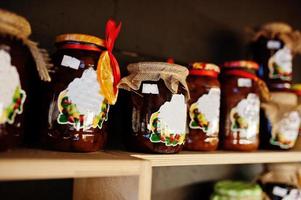 barattoli di vetro con diversi tipi di marmellata e frutti di bosco sugli scaffali di un supermercato o di un negozio di alimentari. prodotti conserviera fatti in casa. fatto con amore. foto