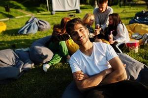 giovane gruppo multietnico di persone che guardano film al poof nel cinema all'aperto. primo piano ritratto di ragazzo divertente. foto