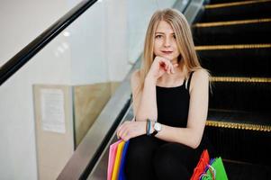 ragazza con le borse della spesa nel centro commerciale sulla scala mobile. foto