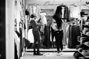 due donne africane che scelgono i vestiti al negozio. giornata di shopping. foto