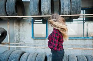 giovane ragazza hipster in camicia a scacchi nella zona di montaggio dei pneumatici. foto