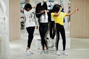 tre donne americane in tute da ginnastica che fanno shopping al centro commerciale di abbigliamento sportivo contro un manichino. tema del negozio di sport. mostra dab. foto