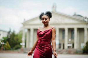 ritratto di una bella giovane donna africana naturale con i capelli afro. modello nero in abito di seta rossa. foto