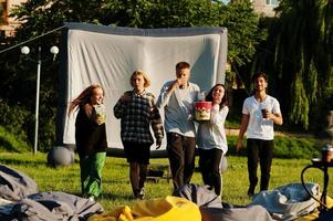 giovane gruppo multietnico di persone che guardano film al poof nel cinema all'aperto. foto