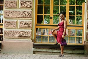 ritratto di una bella giovane donna africana naturale con i capelli afro. modello nero in abito di seta rossa. foto