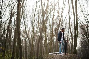 street style uomo arabo in occhiali da vista con longboard su legno. foto